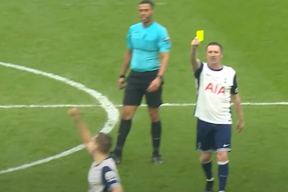 Soccer player shown receiving a yellow card from a referee.