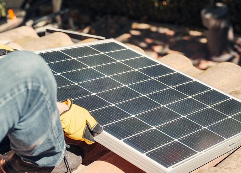 Person installing a solar panel on a roof.