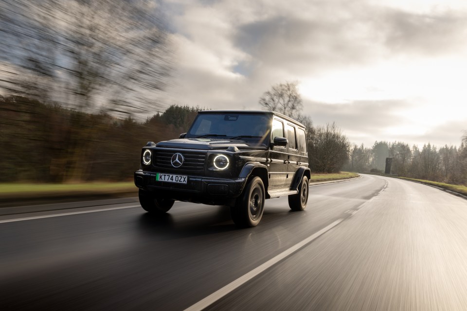 Black Mercedes G-Class driving on a road.