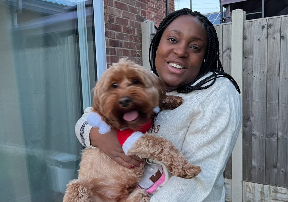Woman holding a dog wearing a Santa outfit.