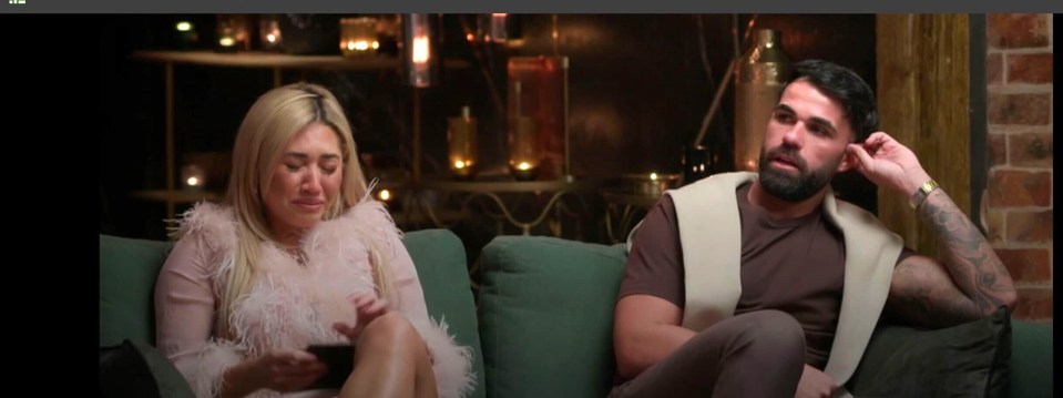 Screenshot of a man and woman sitting on a couch; the woman is crying.