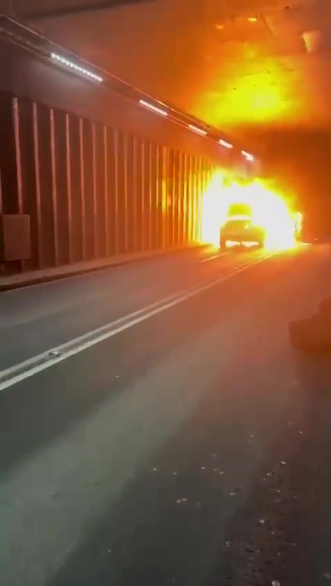 Car engulfed in flames in a tunnel.