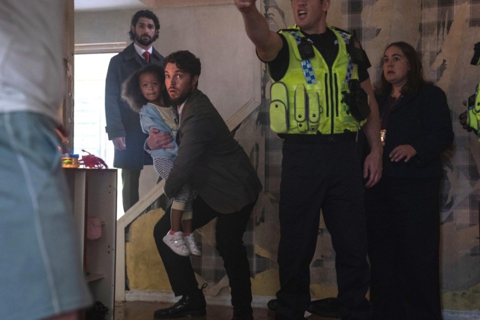 A man holding a young girl, with police officers and other adults present.