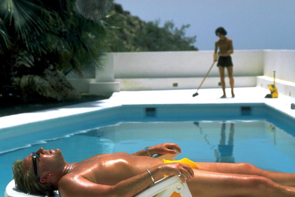 Ray Winstone sunbathing by a pool.