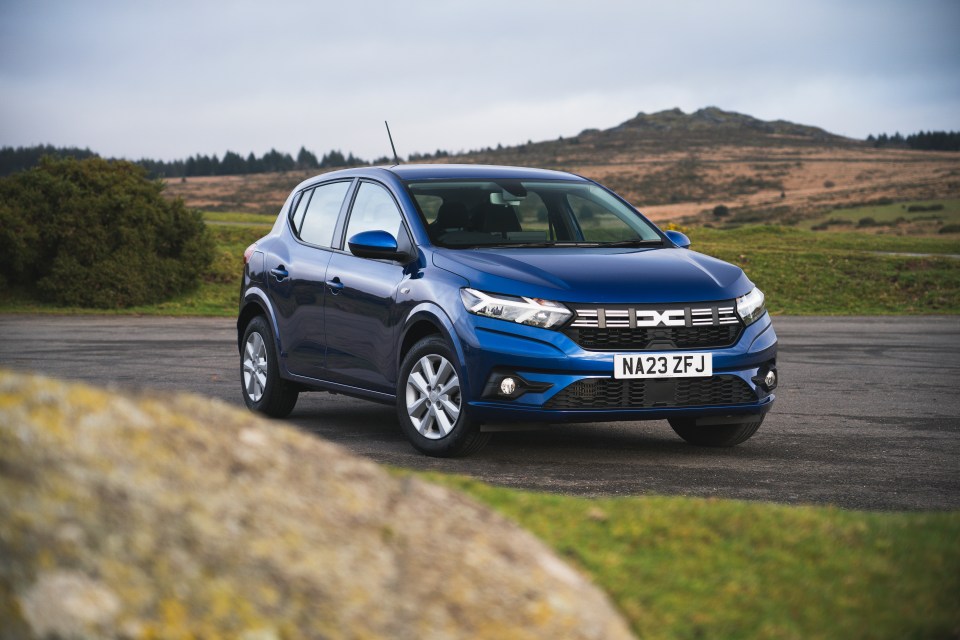 Blue Dacia Sandero parked in a rural setting.