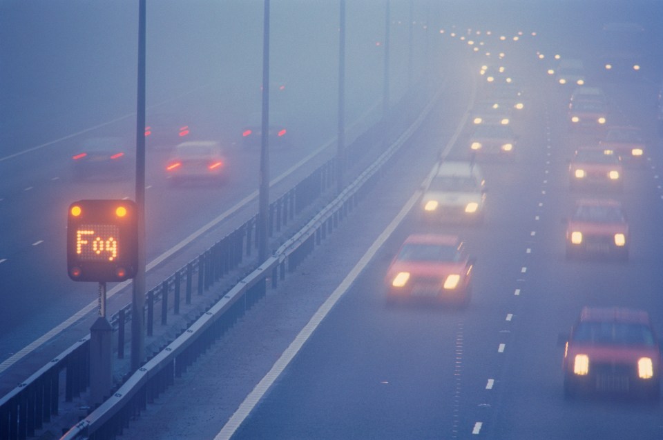 Fog warning sign on a highway in foggy conditions.