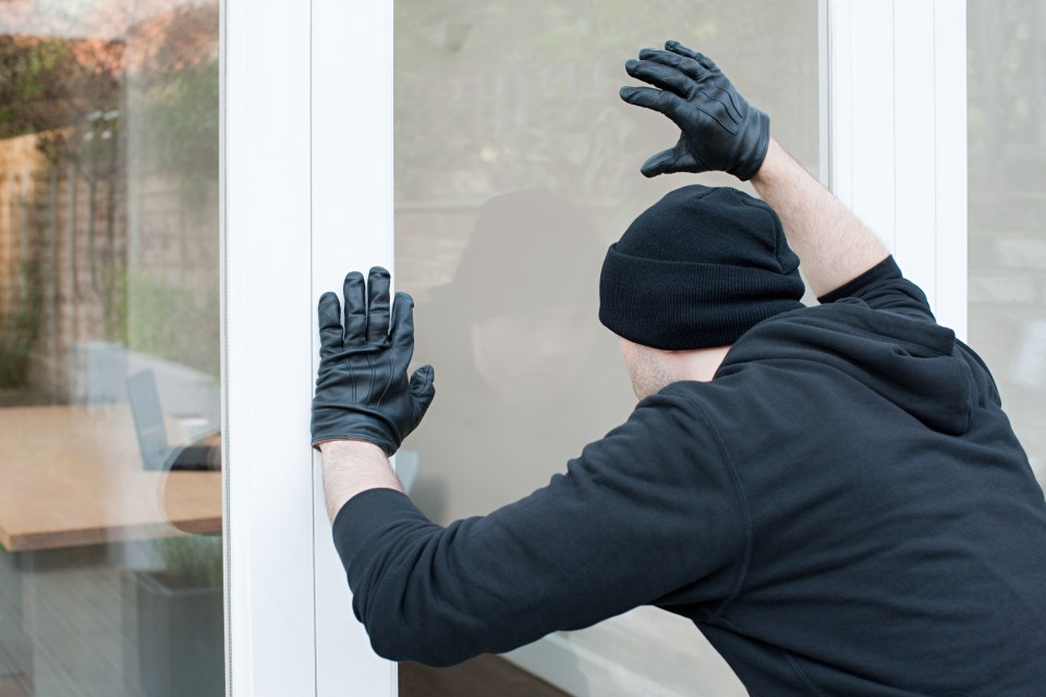 A burglar attempting to break into a house through a patio door.