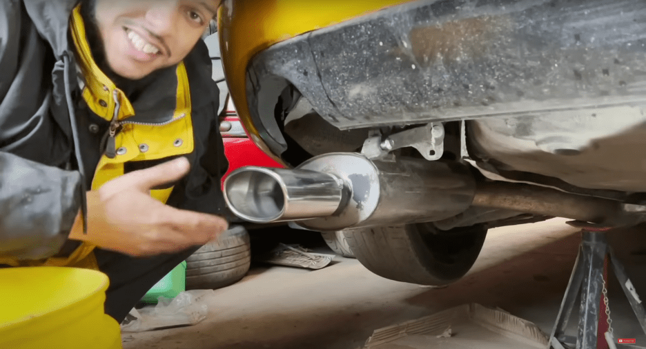 Person showing a car's exhaust pipe.