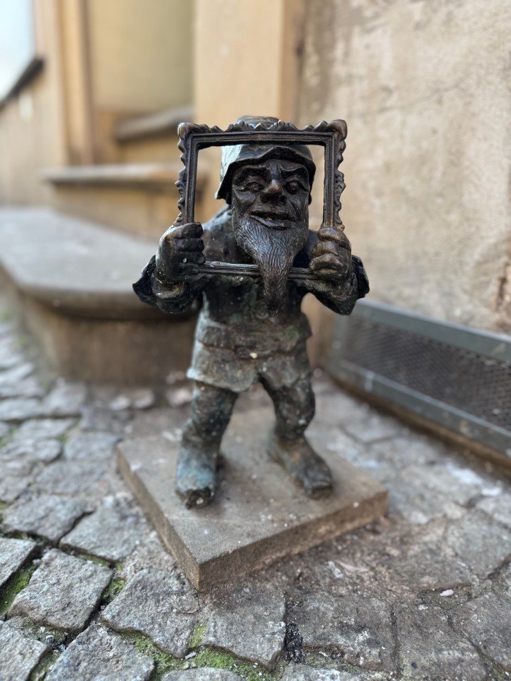 Bronze statue of a gnome holding a picture frame.