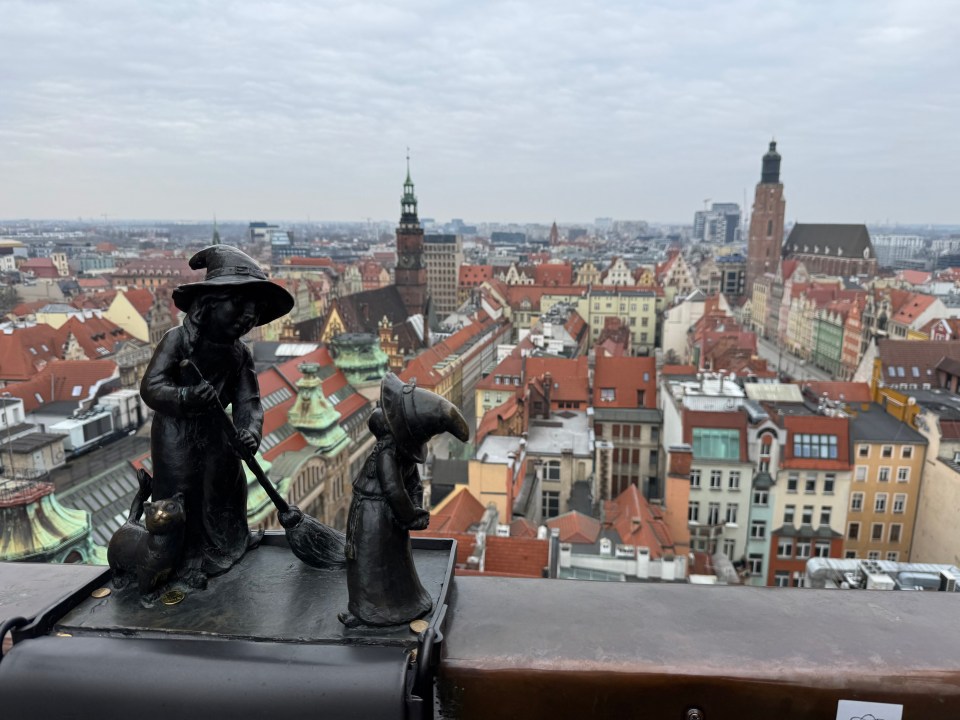 Two small bronze statues overlooking a city.