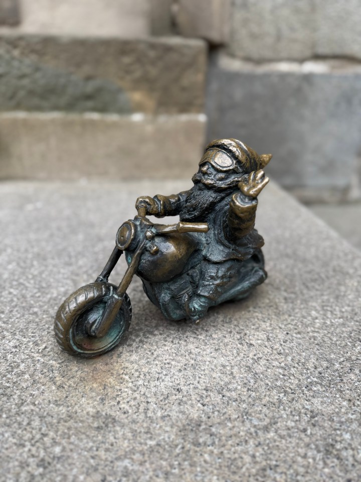 Bronze gnome statue riding a motorcycle.