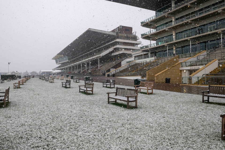 Snow falling on empty benches outside a racetrack.