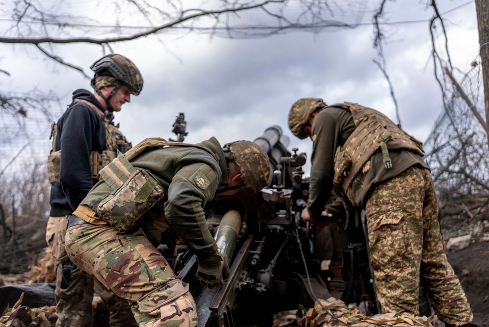 Ukrainian soldiers loading a shell into an M101 Howitzer.