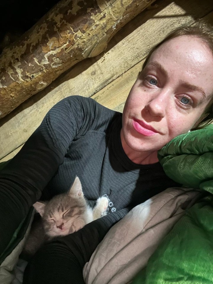 Woman cuddling sleeping kitten.