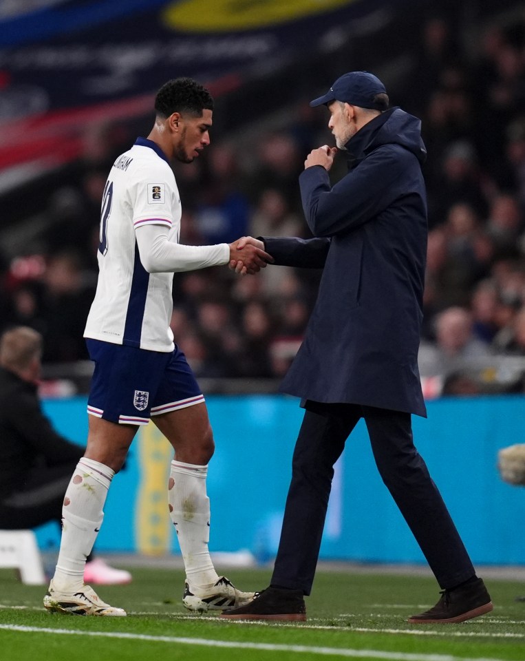 Thomas Tuchel shaking hands with Jude Bellingham on a soccer field.