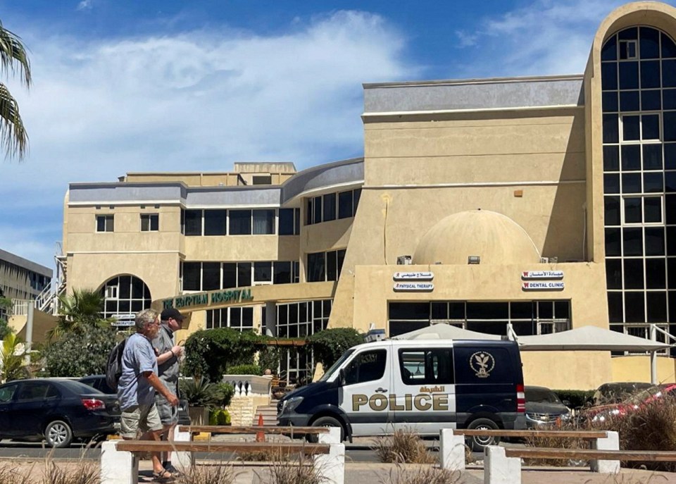 People walk next to an Egyptian police vehicle in front of the hospital where the bodies of foreigners who were killed when a tourist submarine sank off Egypt's Red Sea resort city of Hurghada, and whose whose nationalities are still unknown, are kept in Hurghada, Egypt, March 27, 2025. REUTERS/Stringer