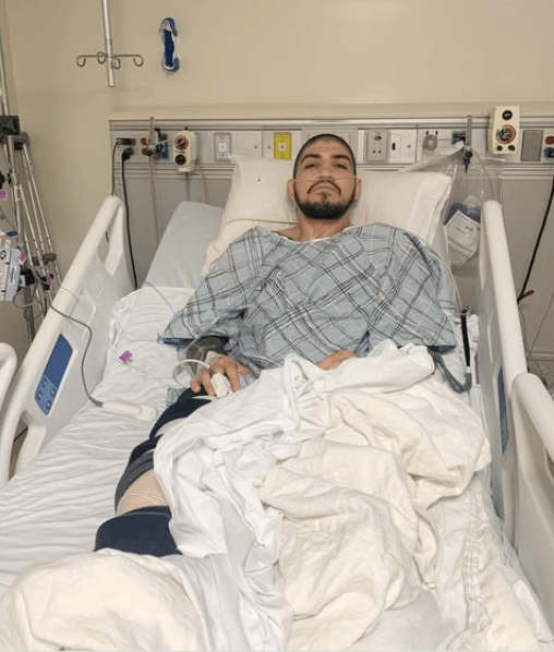 Man in hospital bed with leg injury.