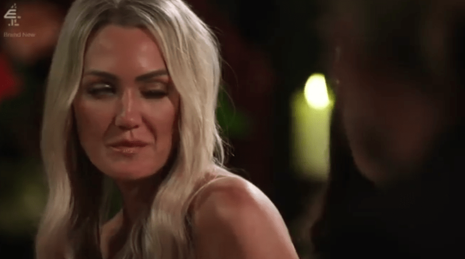 Screenshot of a blonde woman looking sideways at someone out of focus.