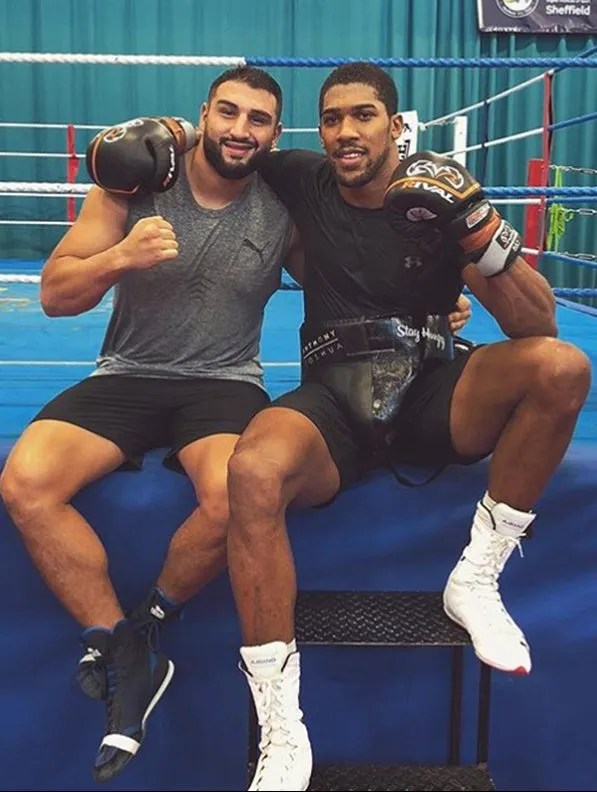 Two boxers sitting together in a boxing ring.