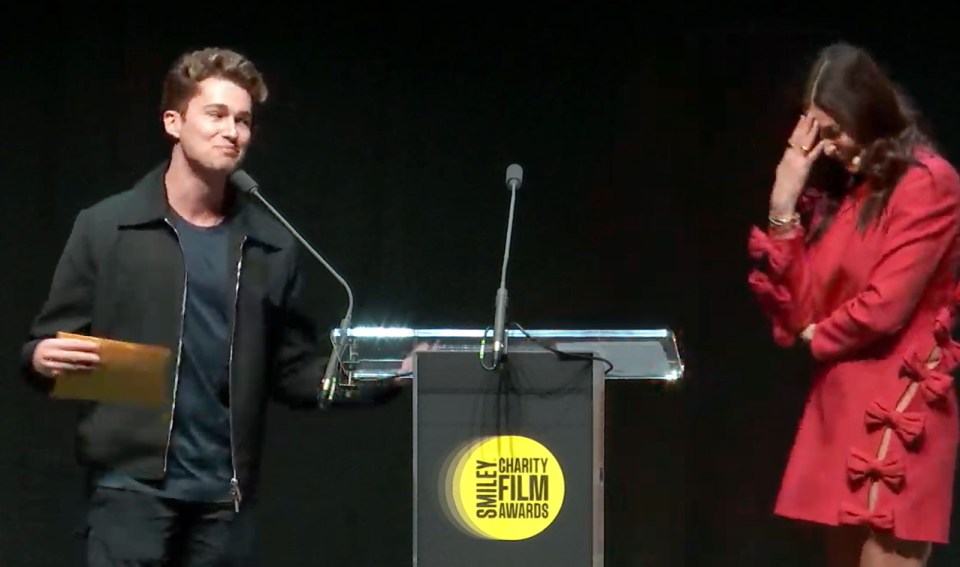 Man and woman at Smiley Charity Film Awards podium.
