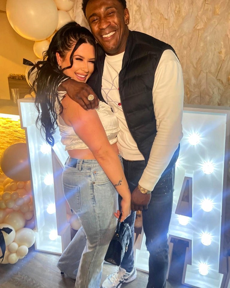 Couple posing together in front of a lighted letter.