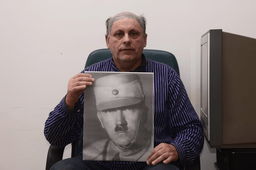 Man holding a photo of Adolf Hitler.