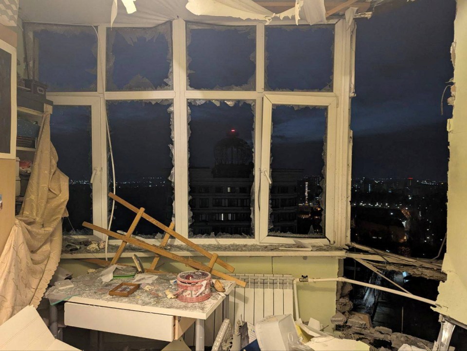Drone-damaged apartment window at night.