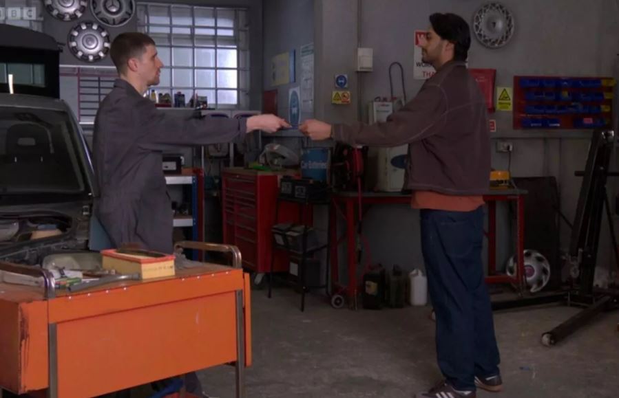 Two men exchanging something in a garage.