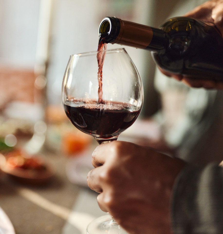 Close-up of a person pouring red wine.