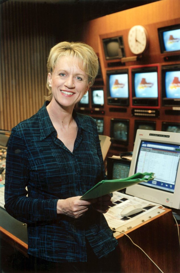 BBC presenter Sally Taylor holding files in a television studio.
