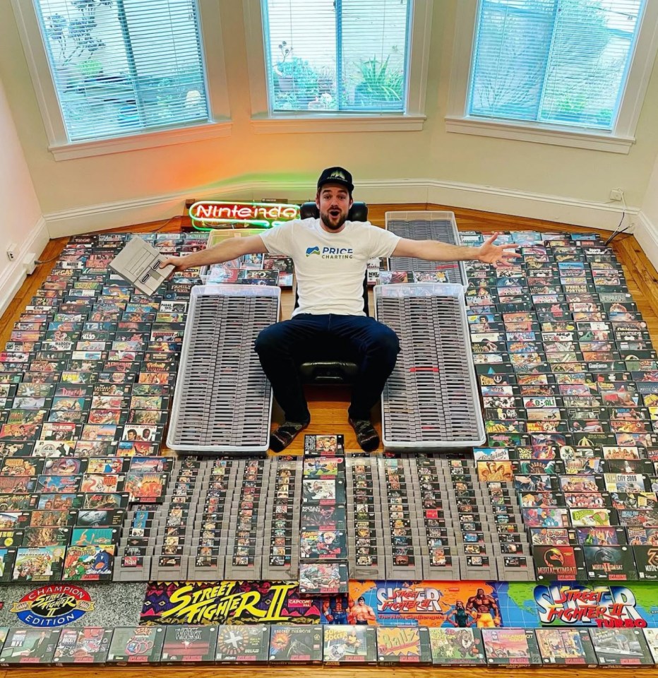 Man sitting amidst a large collection of Super Nintendo games.