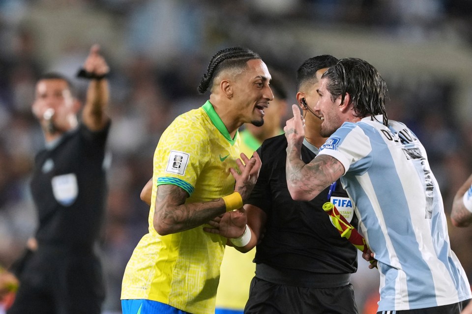 Brazil's Raphinha and Argentina's Rodrigo De Paul arguing with a referee during a soccer match.