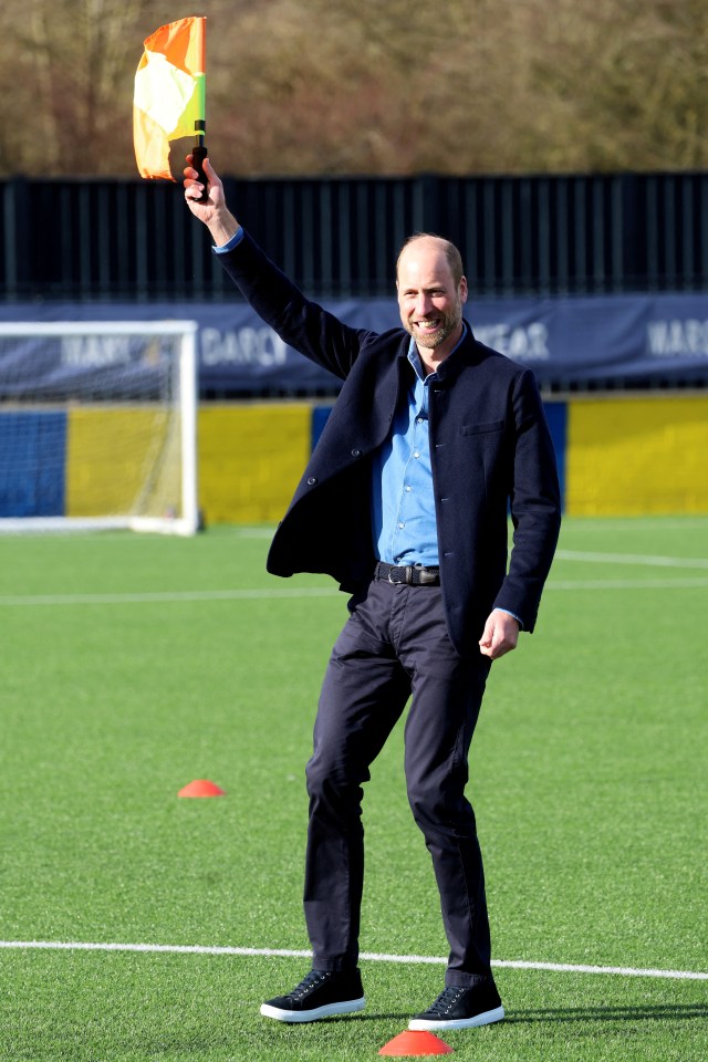 Prince William waves a linesman's flag at a football referee training course.