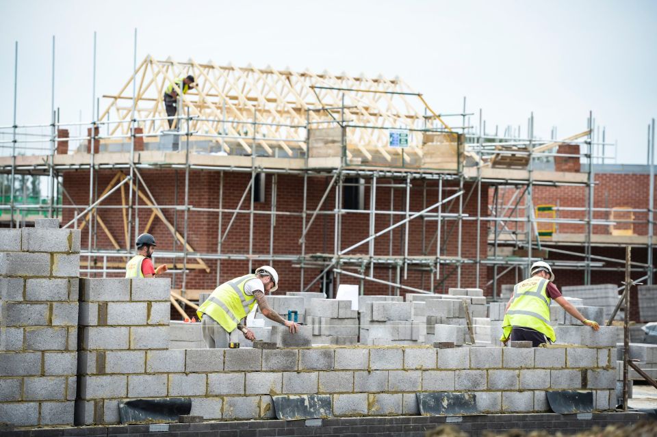Construction workers laying bricks on a building site.