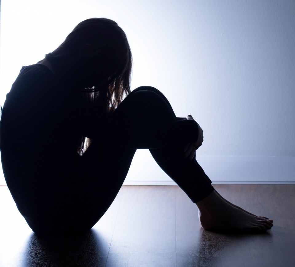 Silhouette of a teenage girl sitting on the floor.