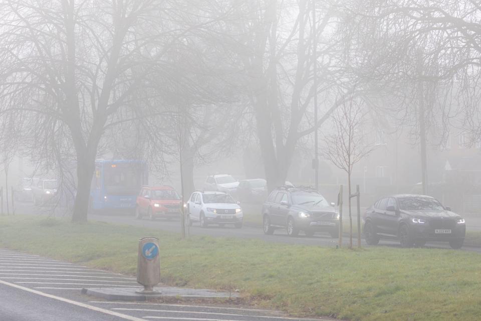 Fog warning sign on a highway in foggy conditions.