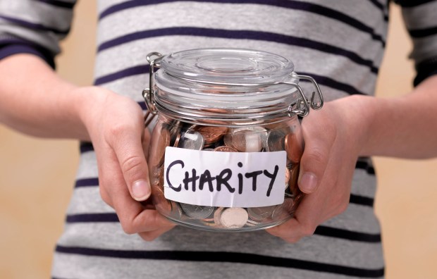 Child holding a jar of coins labeled &quot;Charity.&quot;