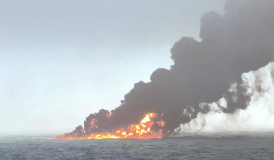 Black smoke billowing from a fire at sea.