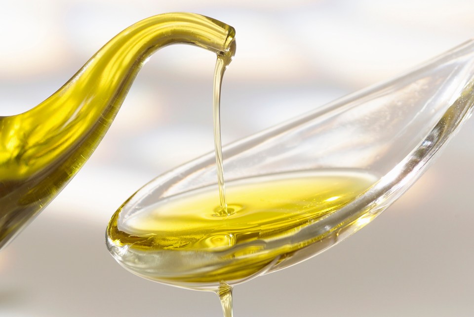 Olive oil pouring into a spoon.