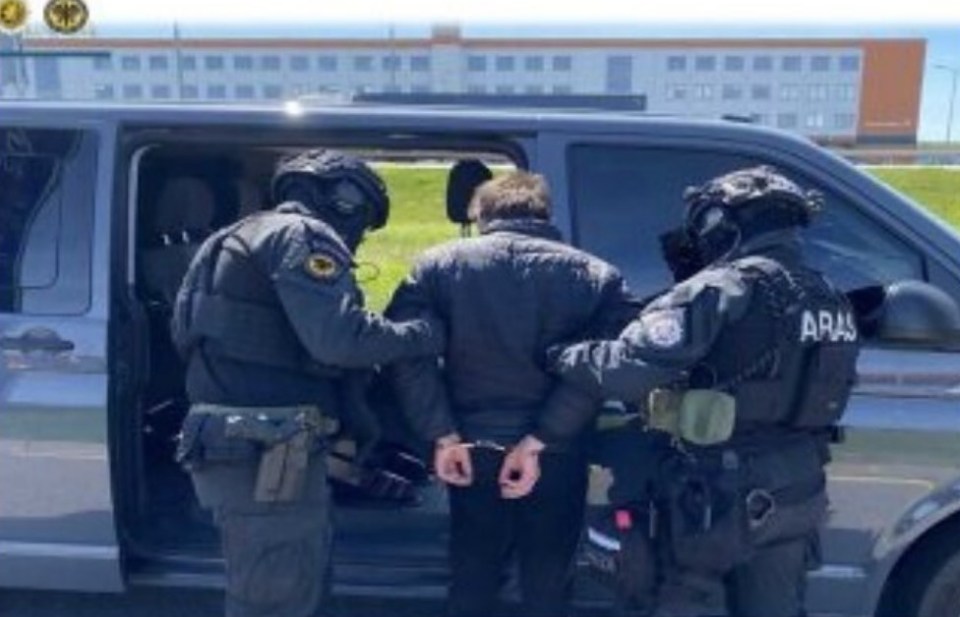 A suspect in handcuffs being detained by police.
