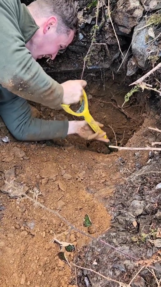 A person rescuing a dog from a hole in the ground.