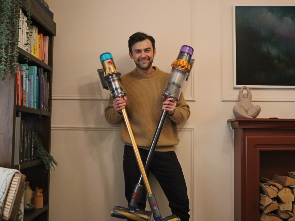 Man holding a Dyson V15 and a Dyson V12 vacuum cleaner.