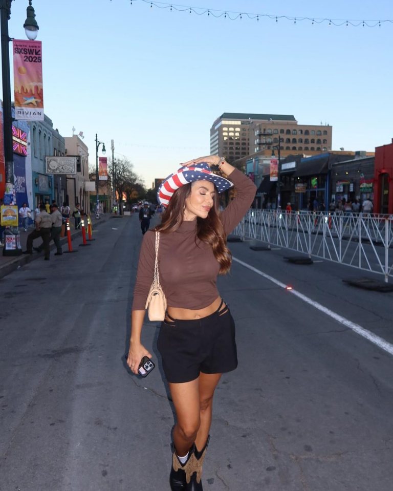Woman in American flag cowboy hat and shorts walking down a city street.