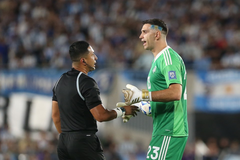 Emiliano Martínez of Argentina speaks with a referee during a soccer match.