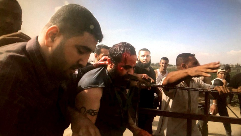 A bloody man being helped by others.