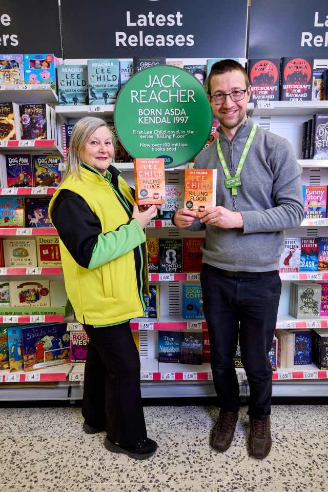 Two ASDA employees holding copies of Lee Child's Jack Reacher novel, "Killing Floor," in front of a book display.
