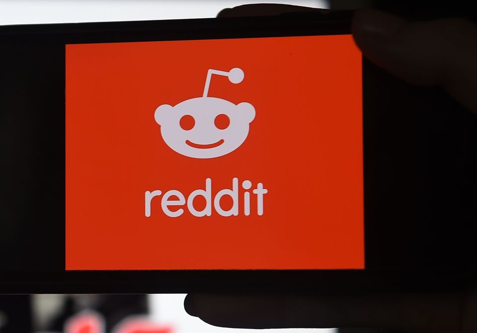 Photo illustration of the Reddit logo on a phone screen.