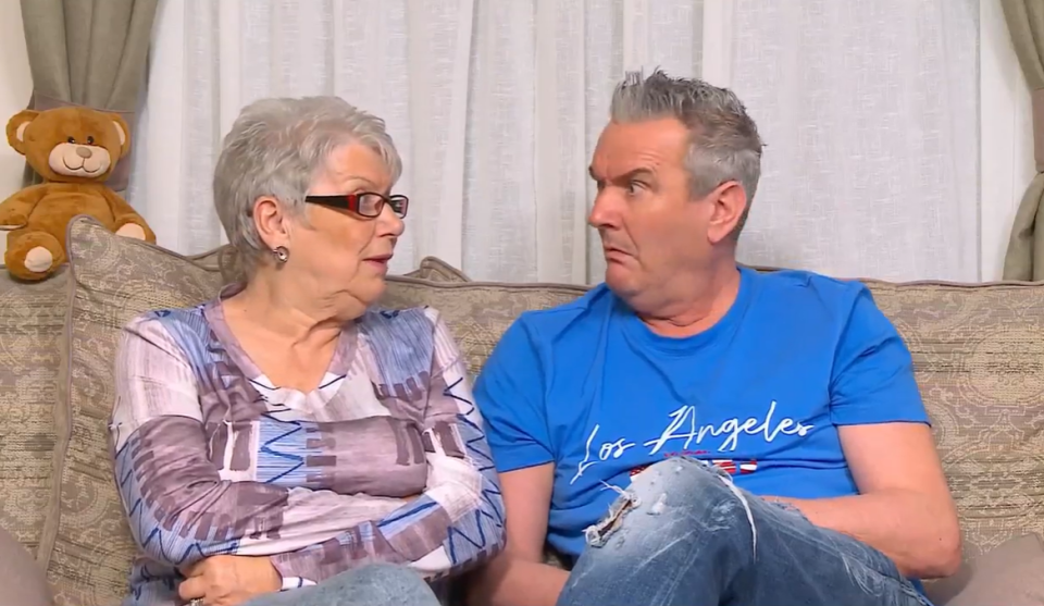 A woman and man sitting on a couch, talking.