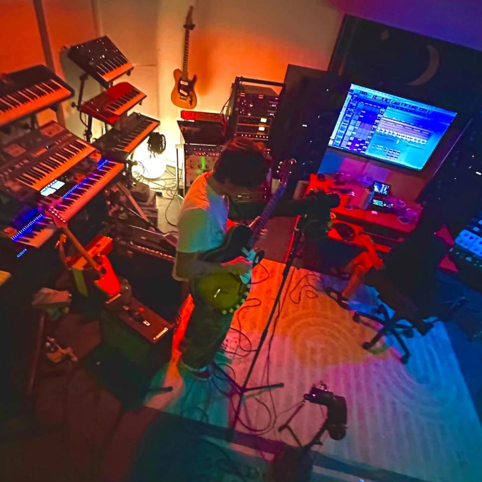 Person singing and playing guitar in a recording studio.