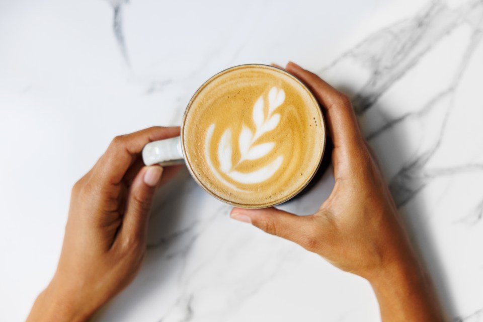 Hands holding a cup of latte with latte art.